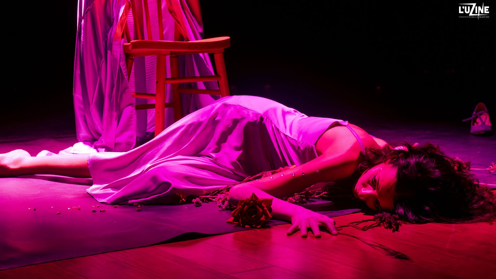 MAHOROBA — performer lying among roses under pink light