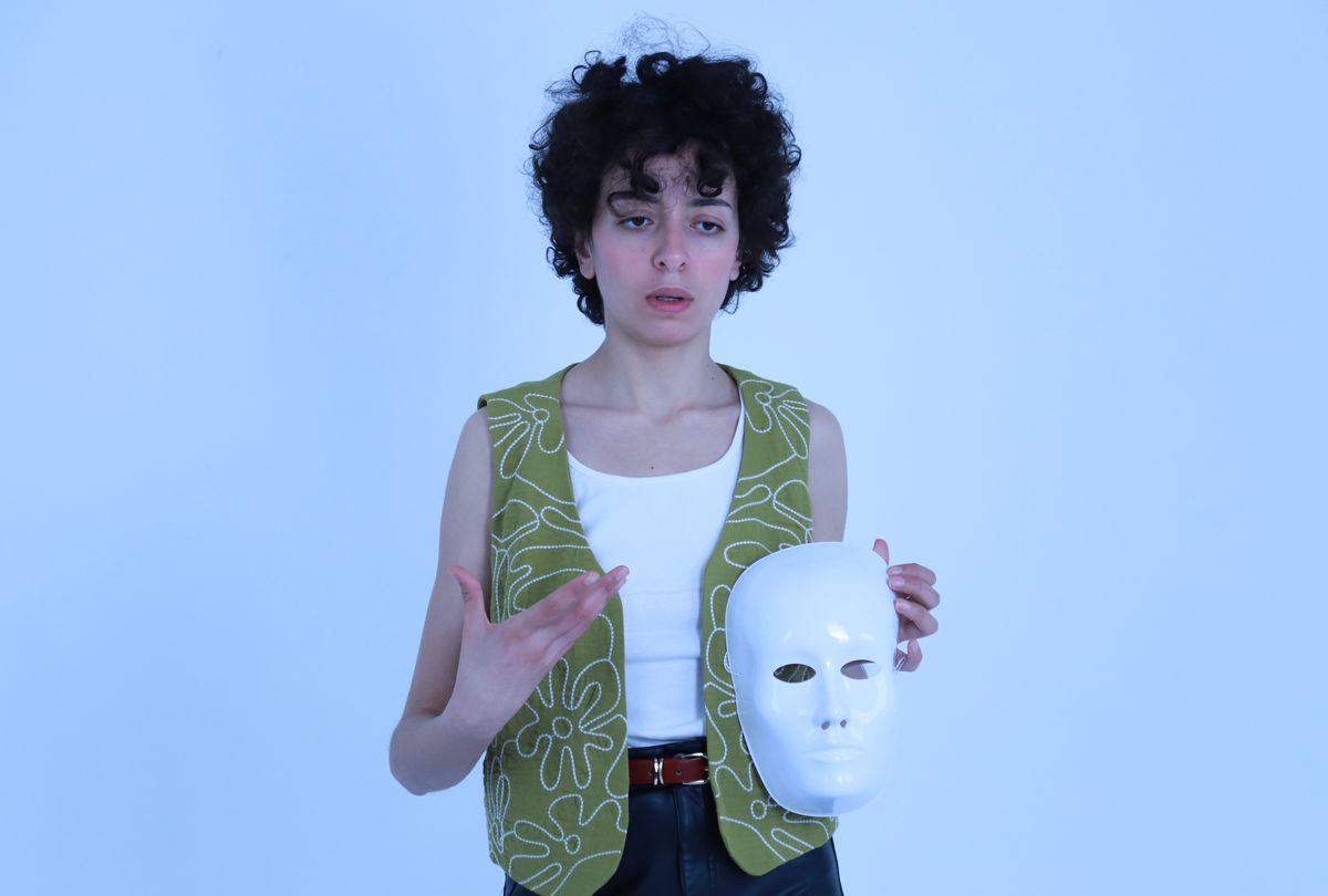 Performer holding a white theater mask